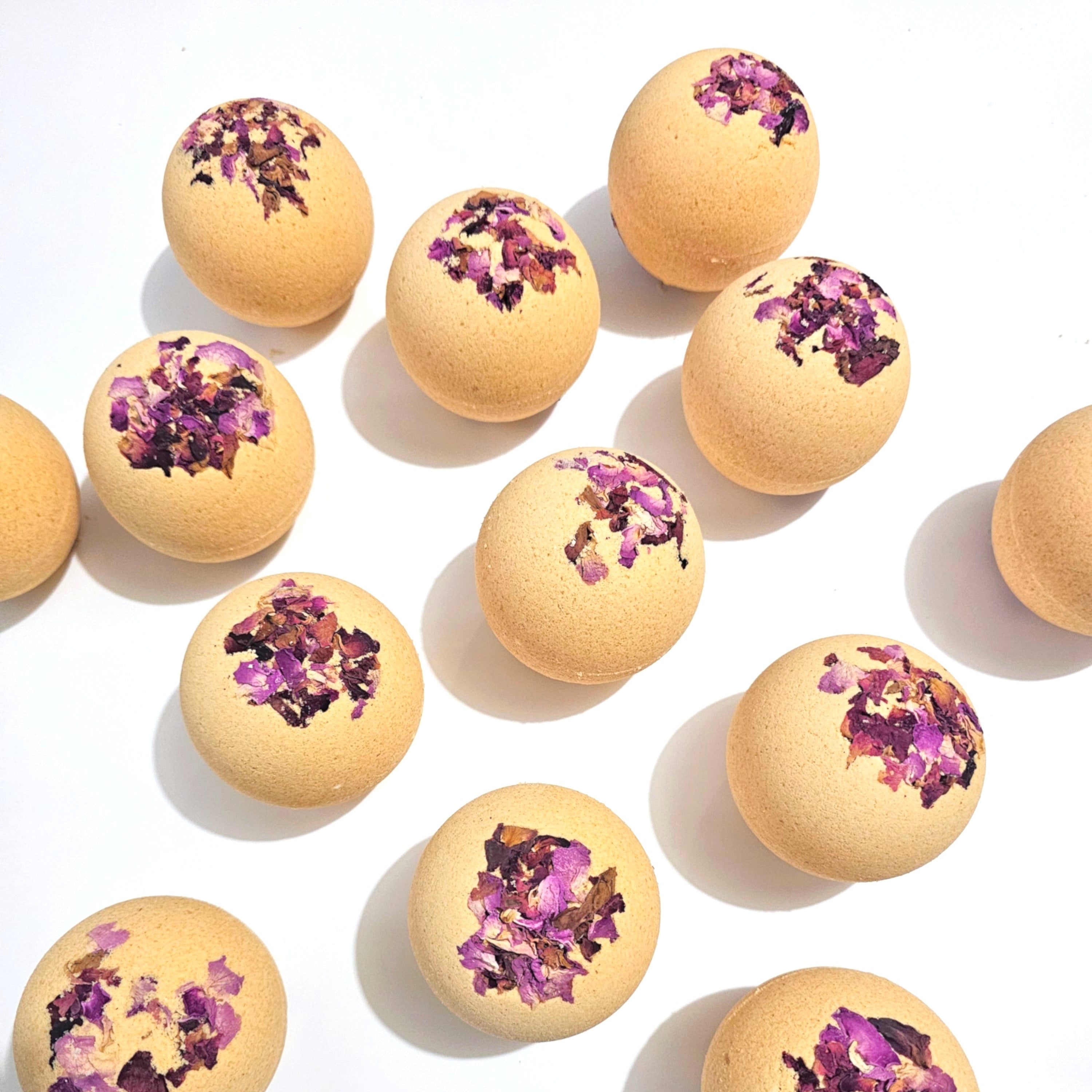 Bath bombs with purple flower petals on a white background